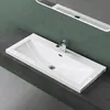 A white rectangular sink with a chrome faucet is shown on a dark gray countertop against a green wall. Produktbild-Vorschau
