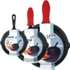 Three cast iron frying pans of different sizes are displayed against a white background, each with a red silicone handle cover and a product information tag. Produktbild-Vorschau