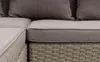 A close-up view of the corner of a sectional sofa with woven rattan base and fabric cushions. Produktbild-Vorschau