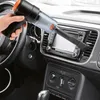 A hand is using a handheld vacuum cleaner to clean the dashboard of a car. Produktbild-Vorschau