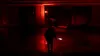 A person holding a glowing object in a dark, red-lit hallway. Produktbild-Vorschau