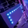 A curved gaming monitor with blue LED lights on the back, set up on a desk with shelves in the background. Náhľad obrázku produktu