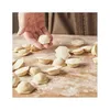 A hand is shown placing a ravioli on a wooden surface covered in flour, surrounded by many other ravioli. Náhled obrázku produktu