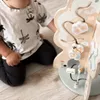 A child is playing with a wooden activity tree toy. Produktbild-Vorschau