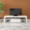 A white TV stand with a television on top, placed in a room with a brown wall and a plant. Náhľad obrázku produktu