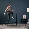A woman is exercising on a trampoline in a living room. Voir les images du produit