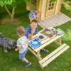 Two children and a dog are playing in a garden near a wooden playhouse and a picnic table. Anteprima dell’immagine prodotto