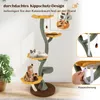 A cat tree with multiple platforms and toys, with two cats on it. The background is a room with a plant and artwork on the wall. There are also inset images showing how to secure the cat tree to the wall. Podgląd zdjęcia produktu