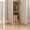 A close-up view of a white cabinet with an open door, revealing shelves with decorative items and binders. Podgląd zdjęcia produktu