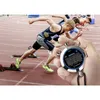 A hand holding a stopwatch in front of runners at the start of a race. Produktbild-Vorschau