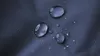 Close-up of water droplets on a dark blue textured fabric. Produktbild-Vorschau