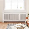 A white radiator cover is shown in a living room setting, in front of a window with blinds. Anteprima dell’immagine prodotto
