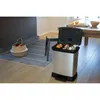 A kitchen scene with a trash can and a basket of fruit. Produktbild-Vorschau