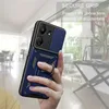 A hand holding a blue phone case with a ring holder, with a blurred background of a room. Produktbild-Vorschau