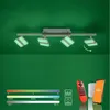 A ceiling light fixture with adjustable spotlights is shown against a green background, with a remote control, a smart speaker, and a smartphone displayed below. Produktbild-Vorschau