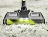 A close-up shot of a vacuum cleaner head with a bright green brush roll on a white carpet. Produktbild-Vorschau