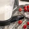 A kitchen scale with a clear container filled with flour is shown on a marble countertop, with raspberries scattered around. Náhľad obrázku produktu