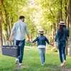 A family walking in a park, carrying a picnic basket. Voir les images du produit