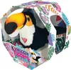 A plush toucan toy inside its retail packaging, which is decorated with tropical leaves and product branding. Voir les images du produit