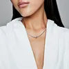 A close-up shot of a woman wearing a silver necklace with a single bead charm. Podgląd zdjęcia produktu