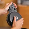 Hands holding a black appliance part with a silver circular component. Produktbild-Vorschau