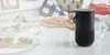 A Bose portable speaker sits on a table set for a meal, with plates of food and glasses of water visible. Produktbild-Vorschau
