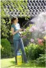 A woman is spraying flowers in a garden with a pressure sprayer. Produktbild-Vorschau