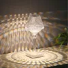 A crystal table lamp casting decorative light patterns on a surface and wall. Náhled obrázku produktu