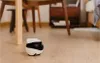A small, white and black robot is on a wooden floor, near the leg of a wooden table. Anteprima dell’immagine prodotto