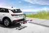 A white car with a bike rack attached to the rear, parked on a paved surface near a beach. Voir les images du produit