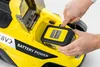 A person is inserting a battery into a yellow lawnmower. Produktbild-Vorschau