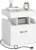 A white nightstand with a drawer and open shelves, featuring a clock and books on top. Podgląd zdjęcia produktu