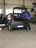 A man is vacuuming the trunk of a car in a garage or workshop. Podgląd zdjęcia produktu