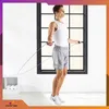 A man is jumping rope in a room with a large window and a shelf with towels. Podgląd zdjęcia produktu