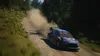 A rally car driving on a dirt road, kicking up dust, with trees in the background. Podgląd zdjęcia produktu