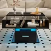 A modern black lift-top coffee table with LED lighting is placed in a living room setting, next to a sofa and on a patterned rug. Voir les images du produit