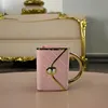 A pink mug shaped like a handbag sits on a pink table, with a plush, ornate couch in the background. Produktbild-Vorschau