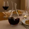 A table setting with a wine decanter, a glass of red wine, a plate of food, and a lit candle. Produktbild-Vorschau