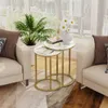 Two nesting round side tables with marble-look tops and gold metal frames are placed next to a sofa in a living room setting. Náhled obrázku produktu
