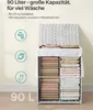 A white woven laundry basket filled with folded linens, with icons and text describing its capacity and features. Produktbild-Vorschau