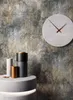 A modern interior scene featuring decorative objects and a clock against a textured wall. Produktbild-Vorschau