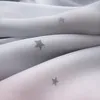 A close-up view of folded gray fabric with a subtle star pattern. Náhled obrázku produktu