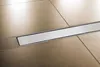 A close-up shot of a modern shower drain installed in a tiled floor. Produktbild-Vorschau