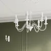 A white chandelier and a wall sconce are shown against a white ceiling and a green wall. Voir les images du produit
