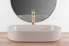 A beige matte washbasin with a gold faucet is shown in front of a mirror. Produktbild-Vorschau
