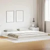 A minimalist bedroom scene featuring a white bed frame with two pillows and a folded blanket. Náhled obrázku produktu
