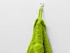 A bright green towel hangs from a white hook on a textured white wall. Náhľad obrázku produktu