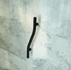 A black curved grab bar mounted on a textured gray wall. Anteprima dell’immagine prodotto
