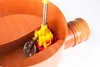 A close-up view of a drain pipe with a yellow and red device inside, likely a backwater valve. Náhled obrázku produktu