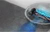 A transparent robotic vacuum cleaner is shown cleaning a carpeted floor, with a cutaway view revealing its internal brush and suction mechanism. Blue light effects illustrate the suction power. Náhľad obrázku produktu
